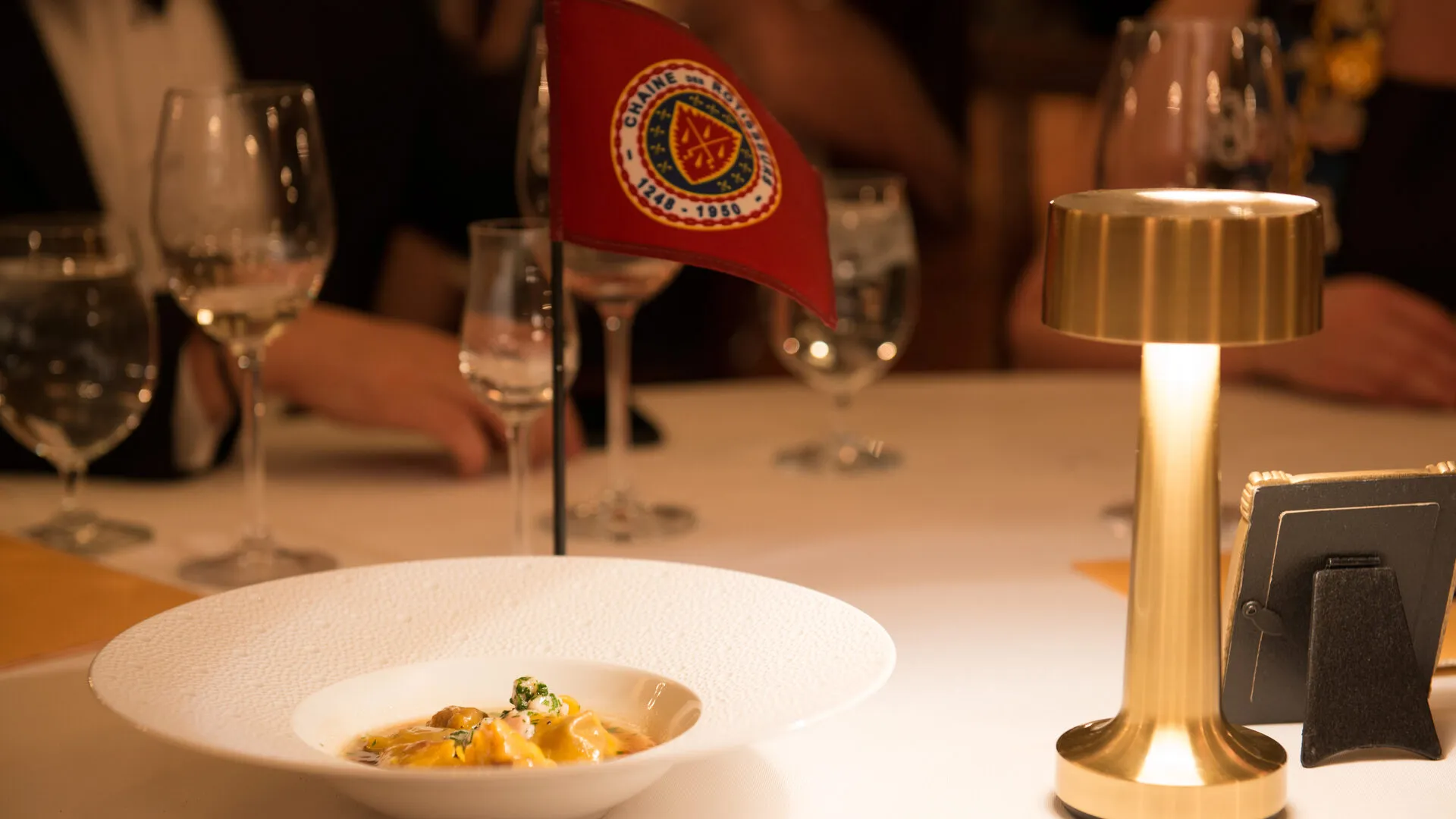 Dining table set with Chaîne des Rôtisseurs flag and fine glassware