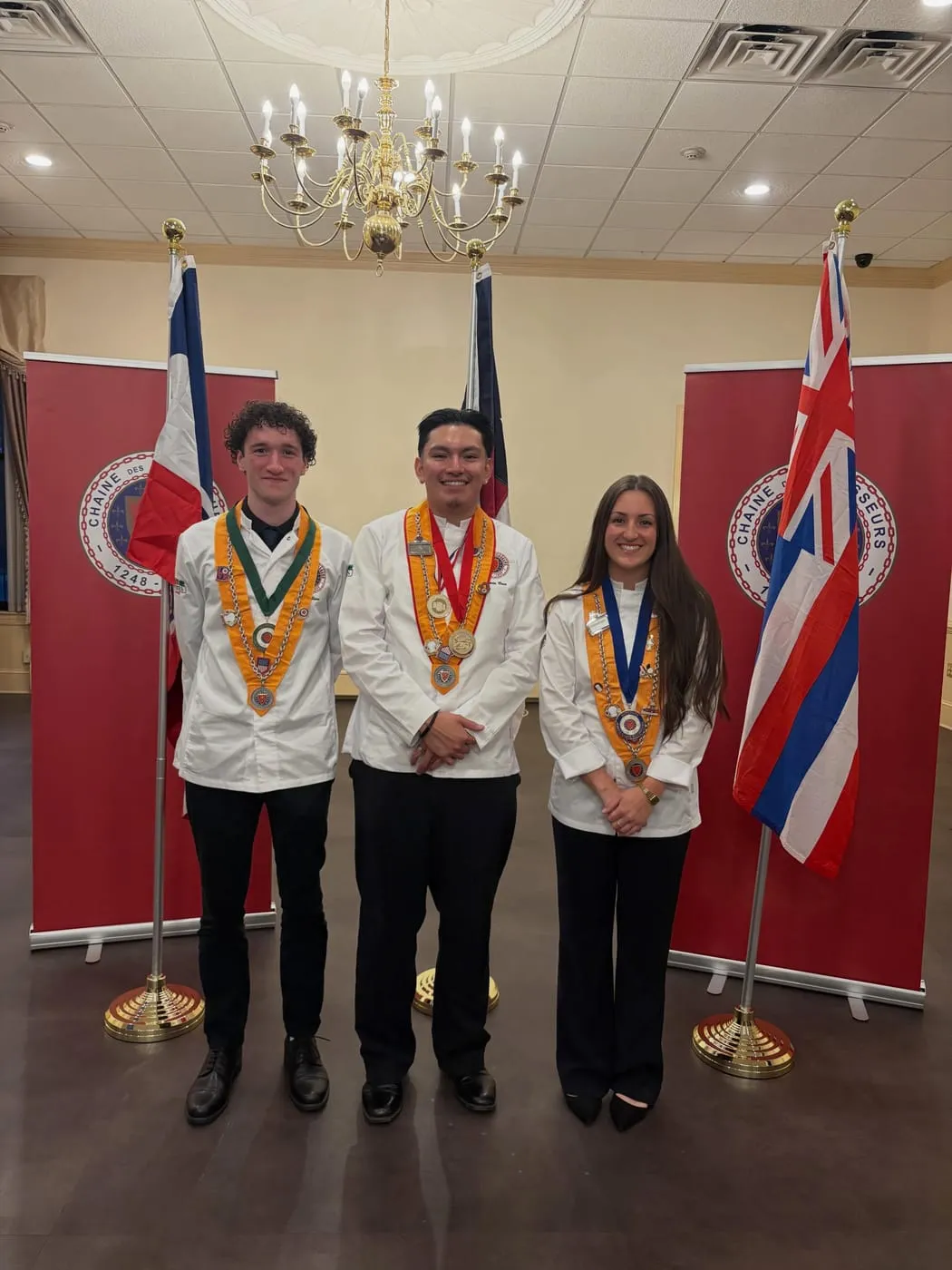 Devin Sierra, Antonio Cruz and Sydney Hilzendeger in chef's whites and Chaîne medals