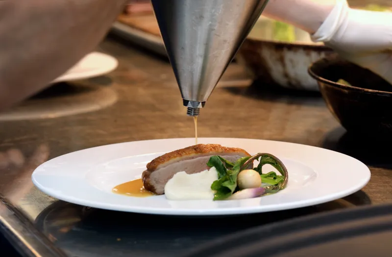 Roasted duck breast finished with natural jus poured from a chef's funnel