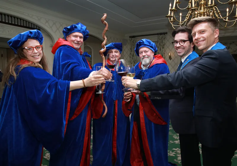Officers and inductees toast together in ceremonial robes