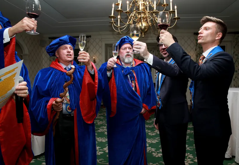 Ceremonial robes raise glasses during the induction toast