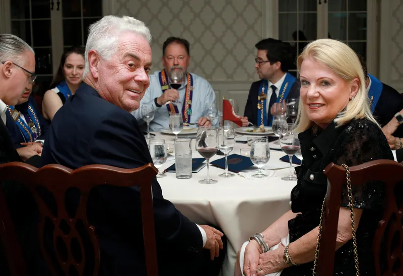 A couple in Chaîne ribbons seated together at dinner