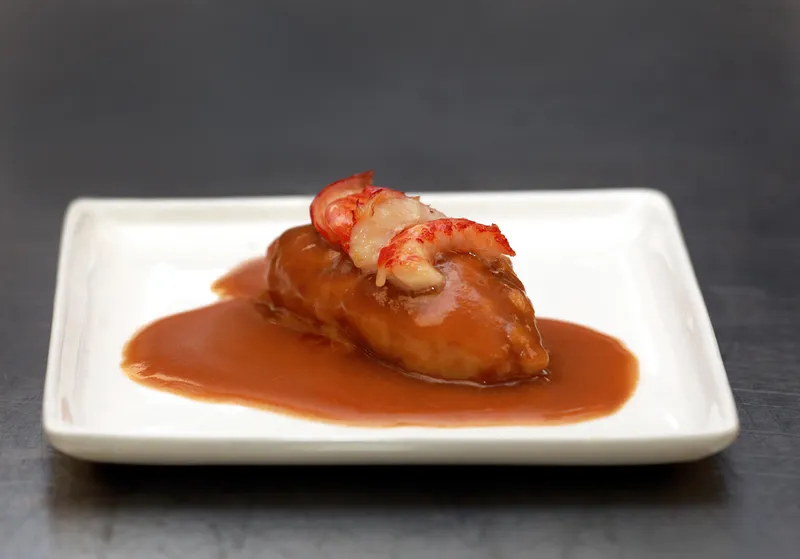 Quenelle de brochet with lobster and sauce nantua on a white plate
