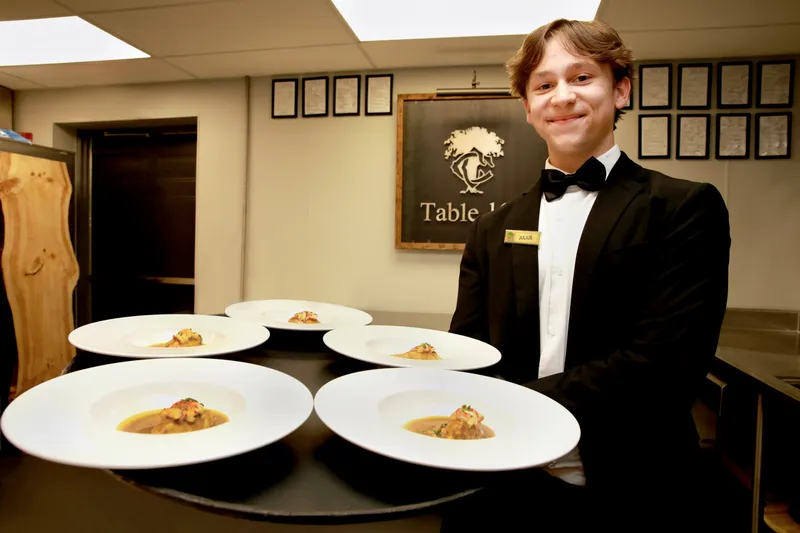 Server presenting a tray of plates at the Table 14 station