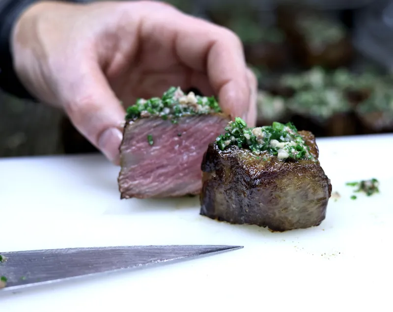 Close-up of a wagyu strip cube with herb-marrow crust on the cutting board