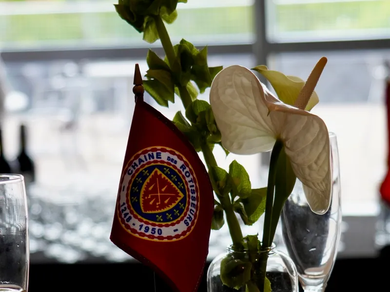 A Chaîne des Rôtisseurs table flag beside an anthurium centerpiece