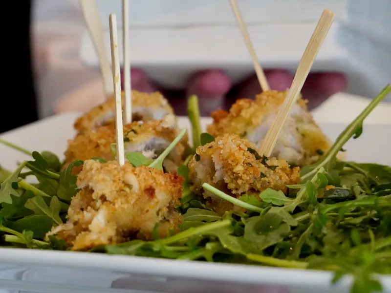 Breaded Sicilian bites served on skewers over arugula