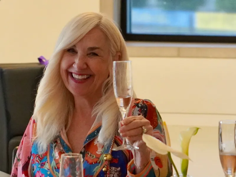 A member raising her glass with a laugh at her table