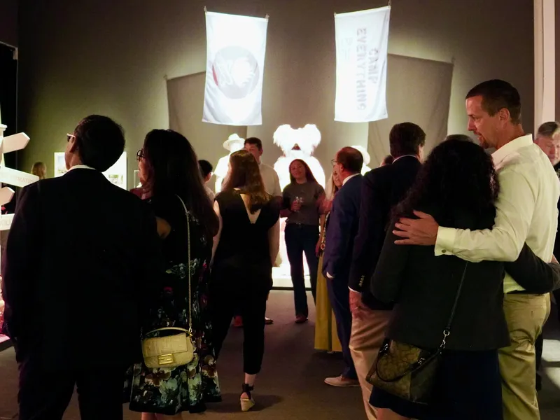 Members viewing illuminated sculptures in a darkened gallery
