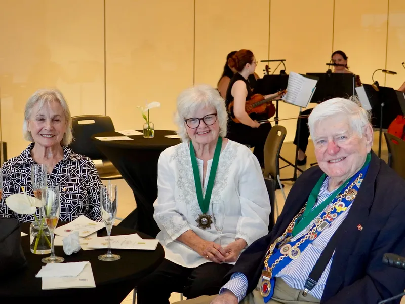 Three seated members with the string quartet playing behind them