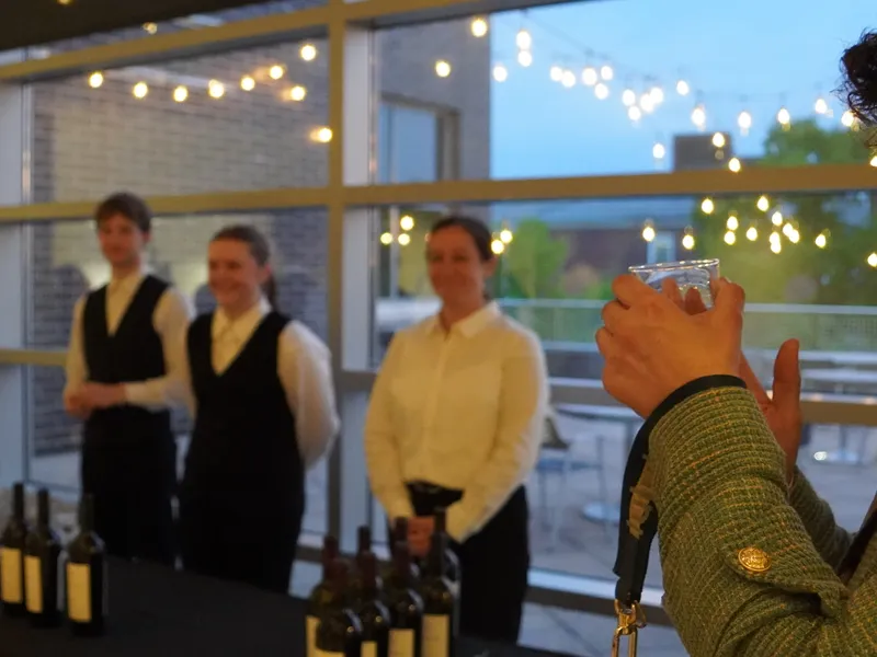 Service staff lined up at dusk as a guest raises a glass